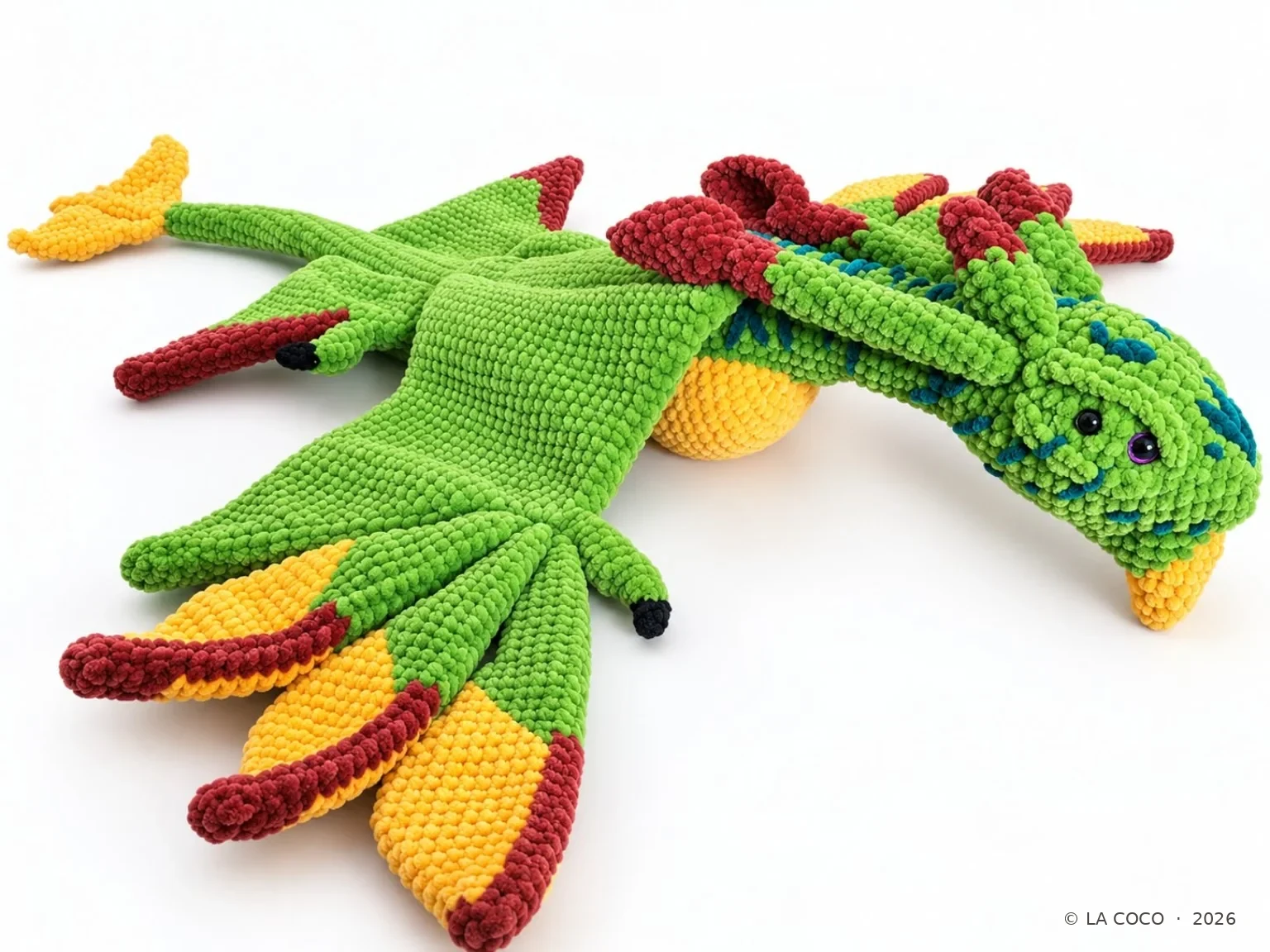 Grüner gehäkelter Drache mit großen grün-gelb-roten Flügeln
