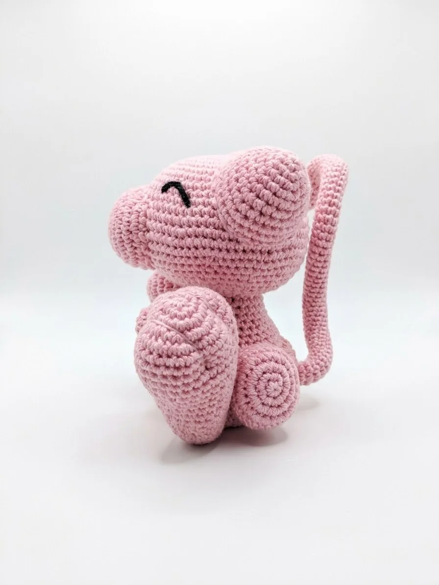 Mew: Eine rosa Figur mit großen Ohren, kleinen Pfoten und langem gebogenem Schwanz. Ansicht 2.