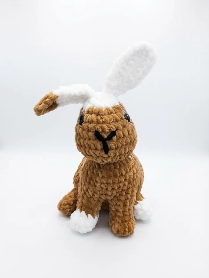 Ein brauner Hase mit langen hellen Ohren und kleinem weißem Schwänzchen. Ansicht 1.