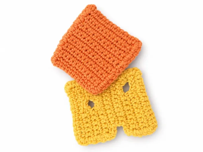 Kinderküche – Orangefarbenes gehäkeltes Quadrat über einer gelben Käsescheibe